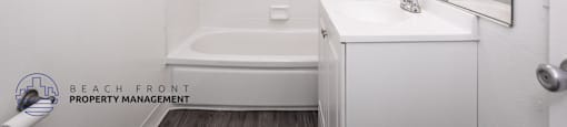 A white bathroom with a bathtub, sink, and mirror.