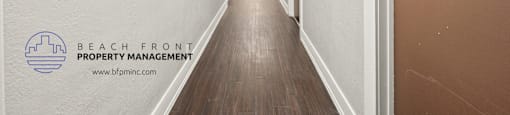 a long hallway with white walls and wood flooring