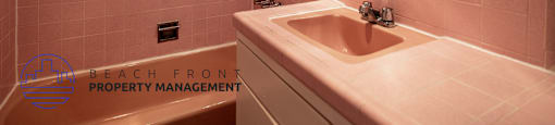 A bathroom with pink tiles and a round mirror.