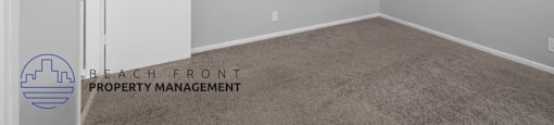 the spacious living room of an apartment with white walls and carpet