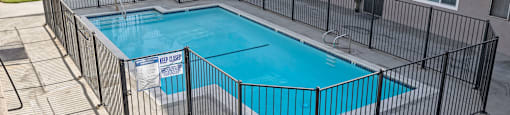 A pool surrounded by a black fence with the words Beach Front Property Management on it.