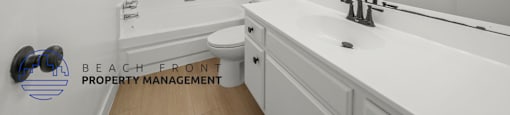A white bathroom with a toilet, sink, and mirror.