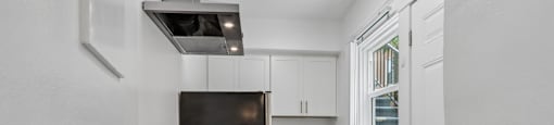 A black stove is in a white kitchen with wood floors.