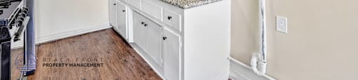 A kitchen with white cabinets and a granite countertop.