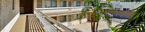 A long balcony with a metal railing and a building in the background.