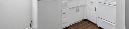 A white kitchen with a refrigerator, stove, and cabinets.