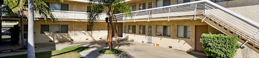 A building with a green lawn in front and palm trees around it.