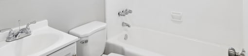 A white bathroom with a toilet, sink, and tub.