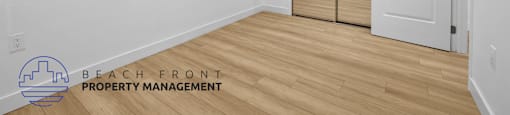 a bedroom with white walls and wood flooring and a white door