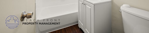A white bathroom with a sink, mirror, and bathtub.