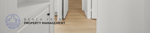 A hallway with white walls and wooden floors, leading to a door at the end.