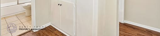 A white cabinet with a door and a shelf is in a room.