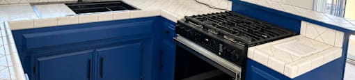 A kitchen with blue cabinets and a black range hood.