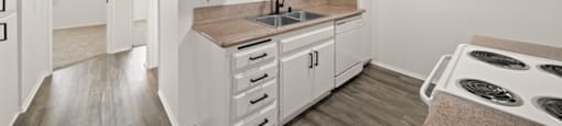 A kitchen with white cabinets and a brown countertop.