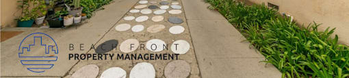 a walkway between two buildings with plants on the side