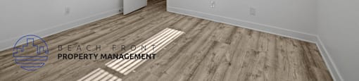 A room with a wooden floor and a door on the left side.