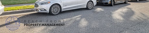 A white car is parked in front of a building with the logo "BEACH FRONT PROPERTY MANAGEMENT" on the ground.
