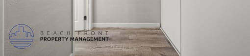 A white hallway with a door and a logo for Beachfront Property Management.