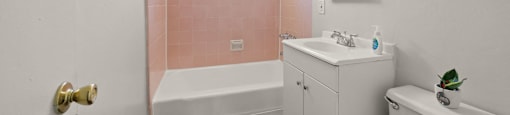 A white bathroom with a pink wall.