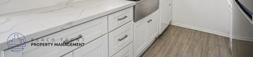 A kitchen with white cabinets and a marble countertop.