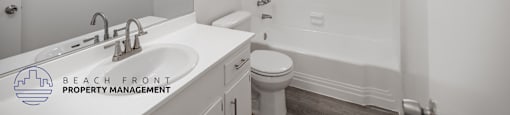 A white bathroom with a sink, mirror, and toilet.