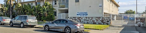 A car is parked in front of a building with a sign that says "LEASING" on it.