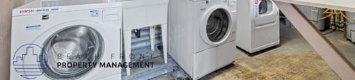 A laundry room with washers and dryers and a sign that says Beauty Front Property Management.