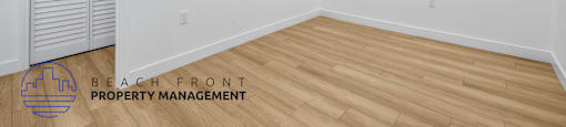 a living room with white walls and wood flooring and a window