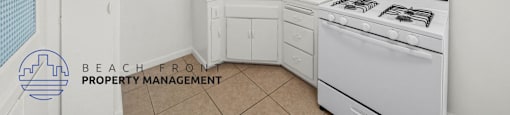 A kitchen with white cabinets and a white stove top oven.
