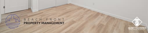 a room with white walls and wood flooring and a ceiling fan