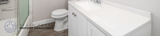 A white bathroom with a toilet, sink, and mirror.
