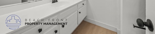 A bathroom with a mirror, sink, and a logo for Beach Front Property Management.