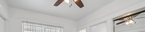 A room with a ceiling fan and a window with blinds.