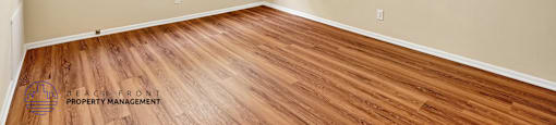 A room with a ceiling fan and wooden flooring.