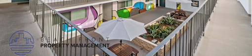 A courtyard with a white fence and a white umbrella.