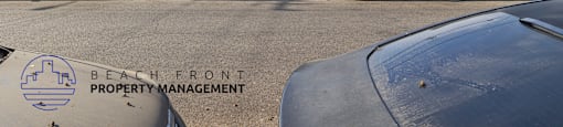 A parking lot with cars and a building in the background with the words Beach Front Property Management.