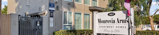 A sign for Monrovia Arms Apartment Homes is in front of a building.