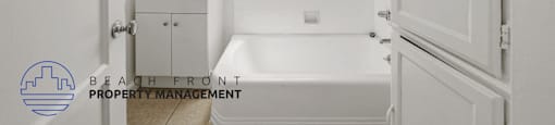 A white bathroom with a tub, sink, and window.