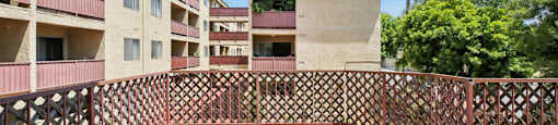 A view of a balcony with a railing and a building in the background.