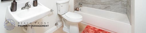 A bathroom with a white toilet, sink, and bathtub.