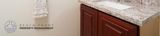A bathroom with a marble countertop and a white towel hanging on the wall.