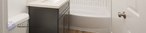 A white bathroom with a black cabinet and a white sink.