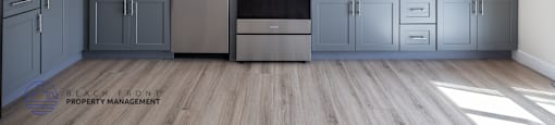 A kitchen with white cabinets and a wooden floor.