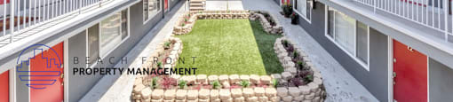 a courtyard of apartments with red doors and a lawn