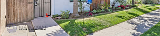 A modern house with a white and brown exterior and a black gate.