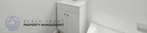 A white bathroom with a sink and a window.