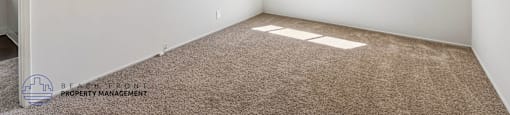 A room with a window and a carpeted floor.