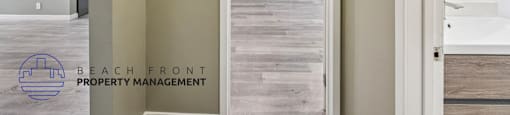 A room with a doorway leading to another room with a logo of Beach Front Property Management.