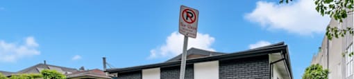 a house behind a fence with a no parking sign