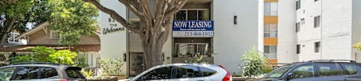 A silver car with the word "CONTENT" written on it is parked in front of a building with a "NO LEASING" sign.